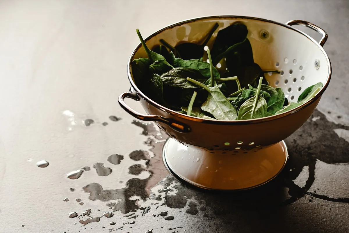 Verre de boisson à base de fer à côté de légumes verts frais et d'agrumes sur une table lumineuse