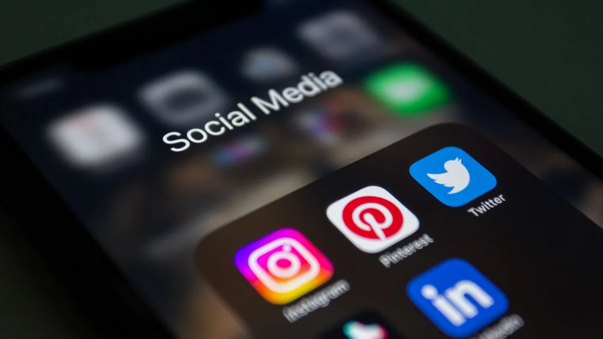 Mains tenant un téléphone affichant des réseaux sociaux avec contenus pharmaceutiques, entouré de documents de recherche