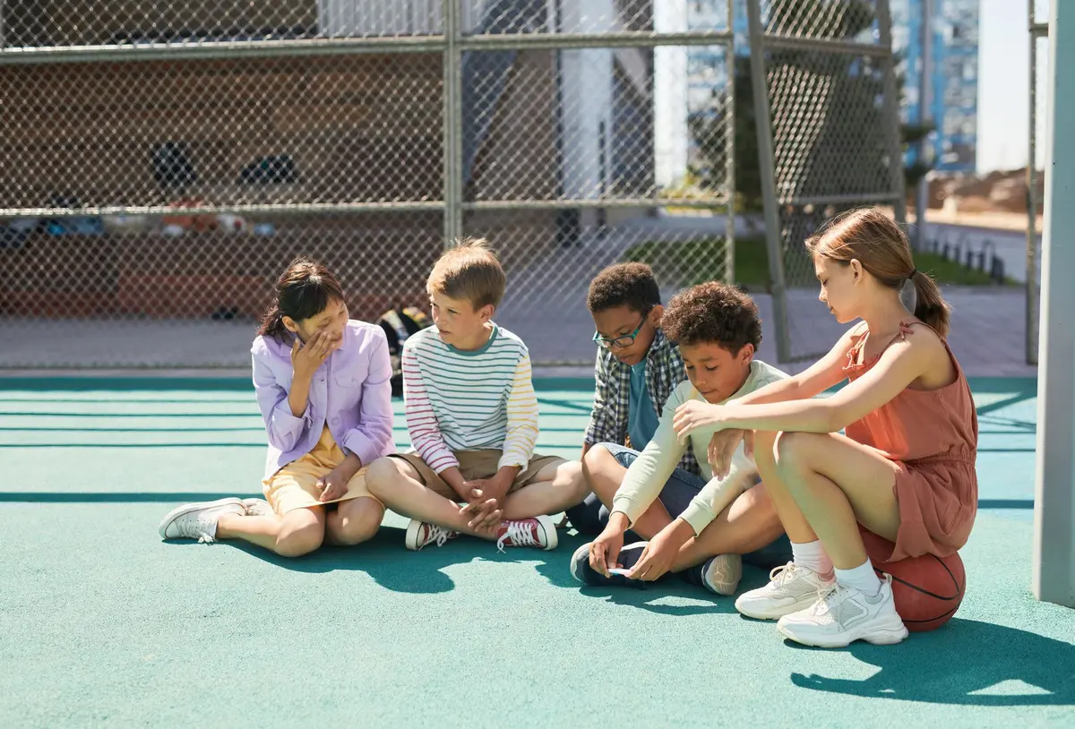 Des enfants jouant ensemble dans une cour d'école, montrant des interactions entre pairs.