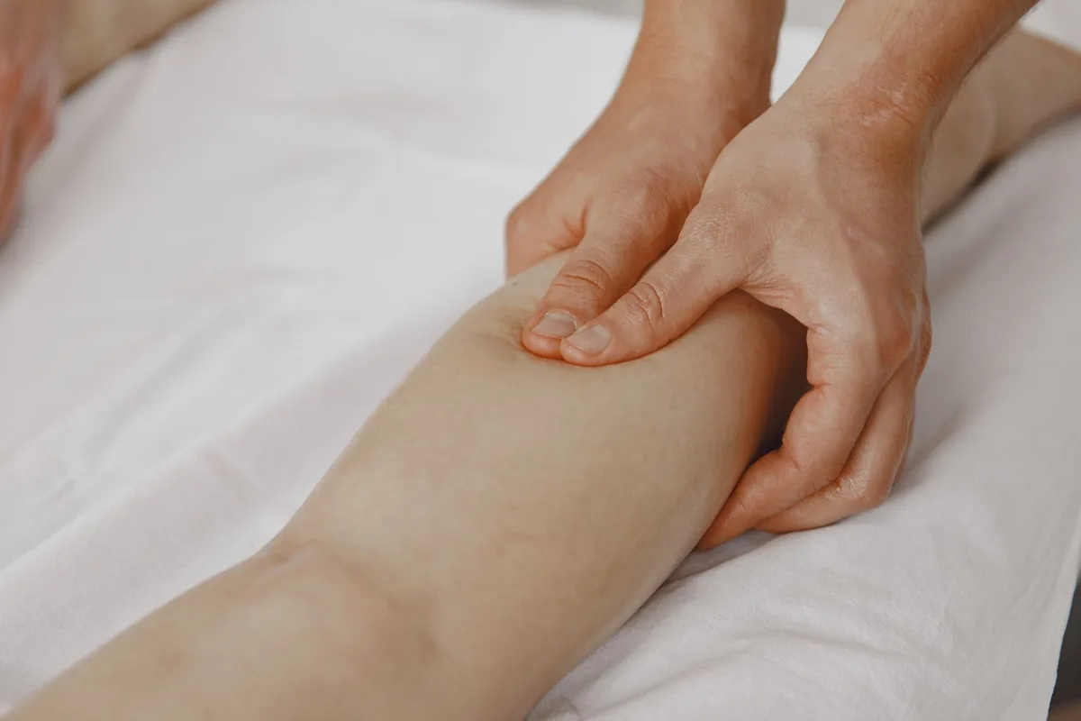 Mains effectuant un auto-massage sur la cuisse et le mollet
