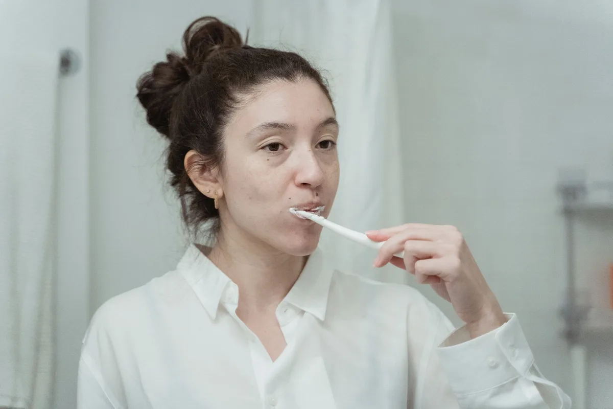 Brosse à dents avec dentifrice blanchissant devant un miroir de salle de bain, lumière douce du matin.