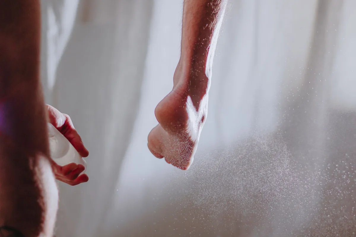 Application du spray déodorant sur pieds propres et secs avant d'enfiler des chaussures