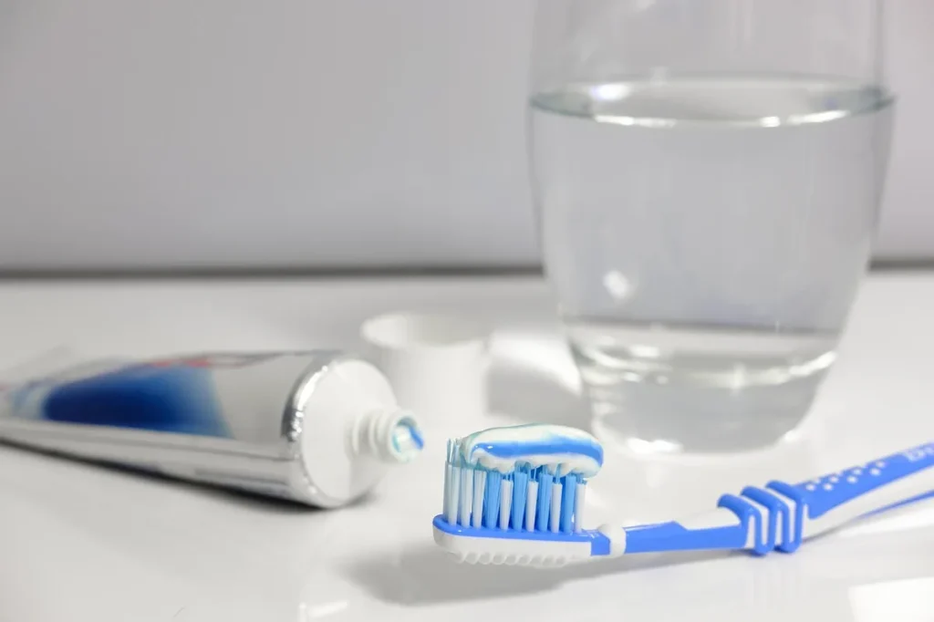 Brosse à dents et tube de dentifrice générique sur un lavabo, main prête à se brosser