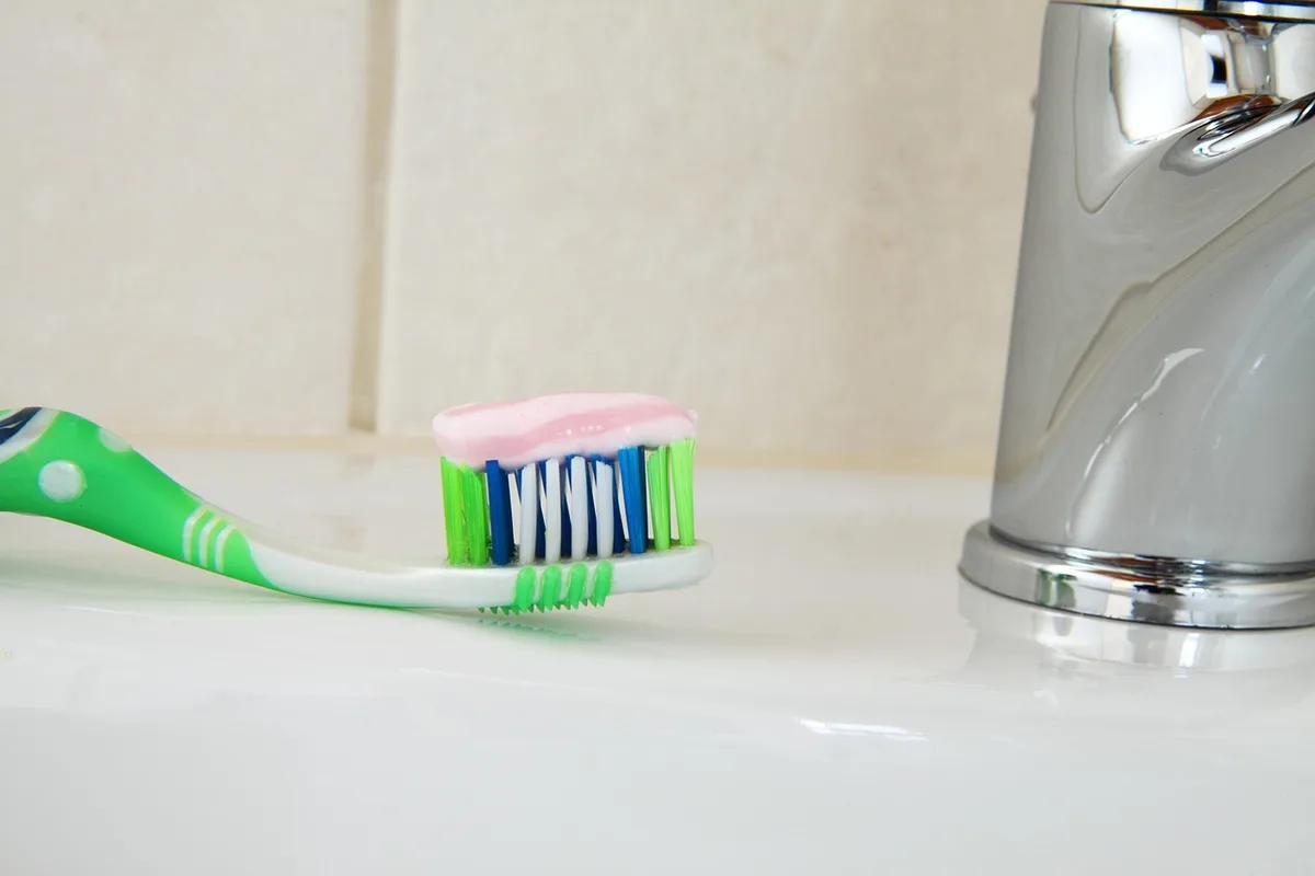 Tube de dentifrice sur lavabo avec mousse et serviette, ambiance fraîche et épurée