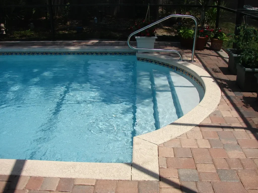 Piscine intérieure en journée, jambes en mouvement, palmes et planche au bord