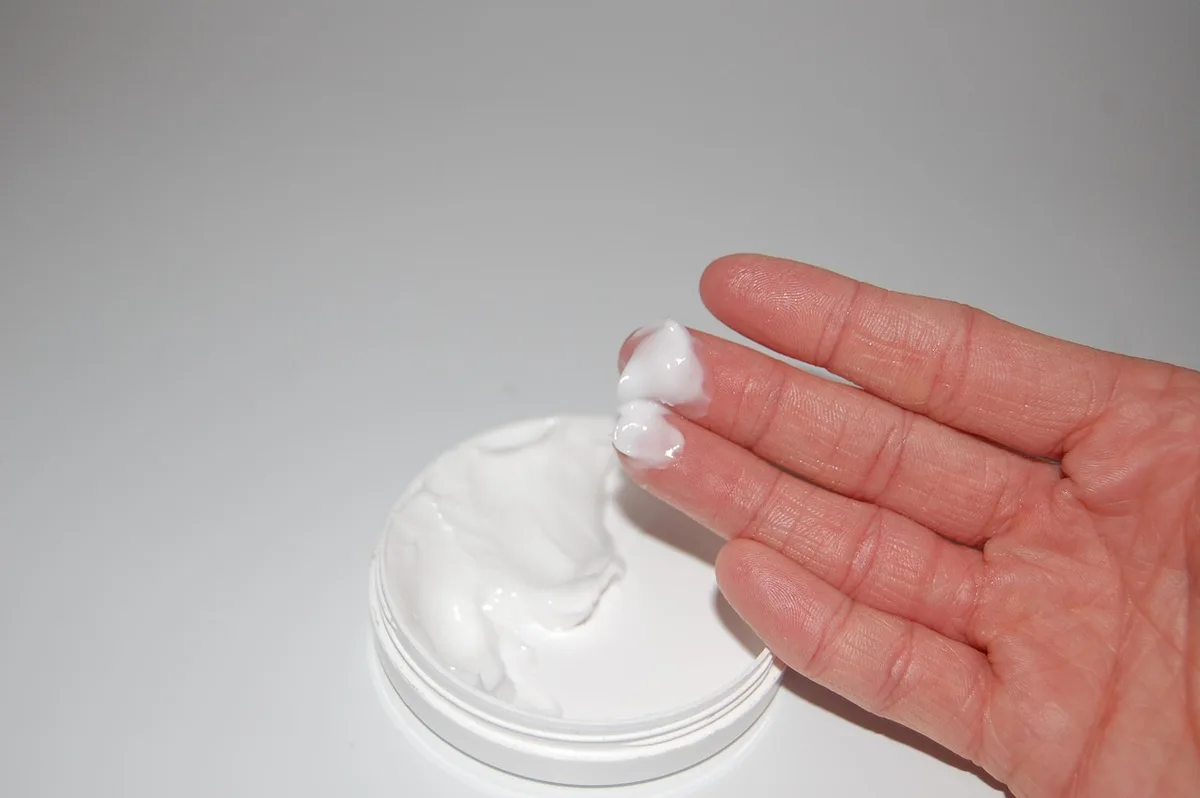 Mains appliquant une crème sur la cuisse avant le coucher