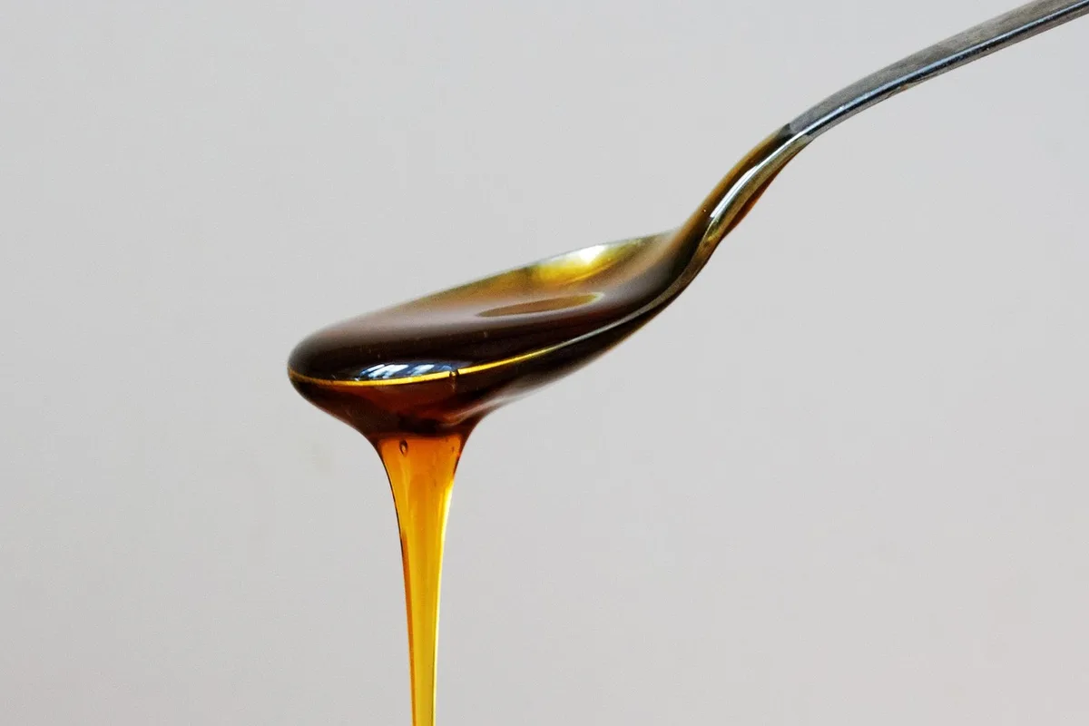 Pot de miel et petites pastilles de propolis sur une table