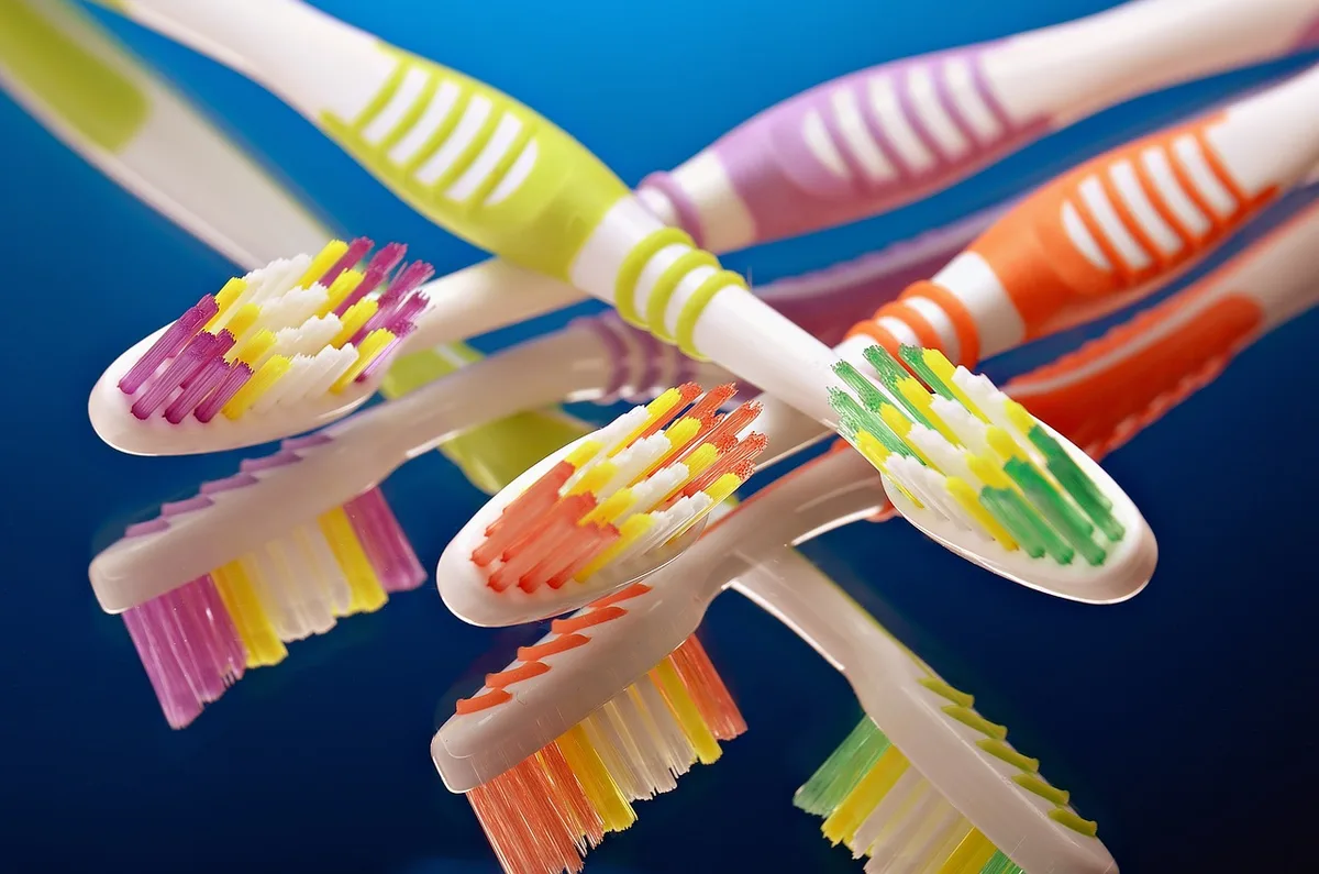 Main tenant une brosse à dents électrique près d'un lavabo lumineux