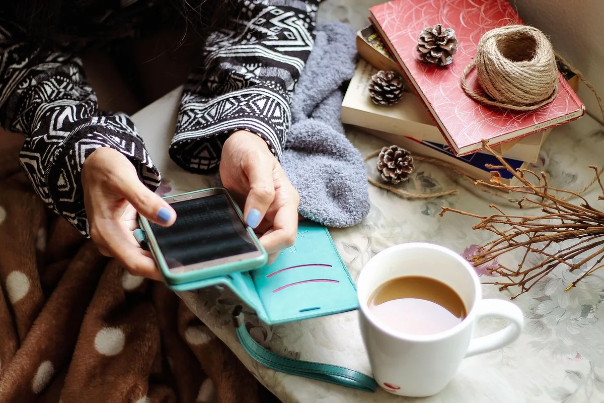 Tasse de café sur une table de cuisine ensoleillée avec un carnet et une main