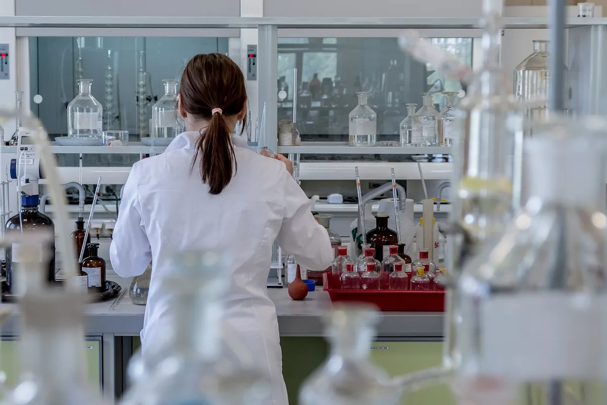 Technicien en blouse manipulant des échantillons de compléments dans un laboratoire clair