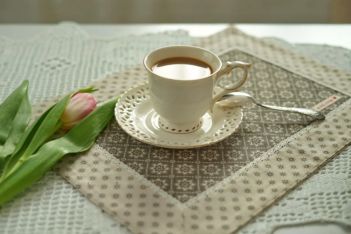 Tasse de café noir posée sur une table lumineuse