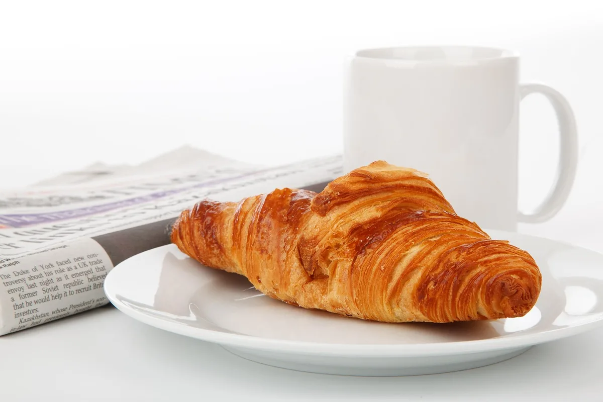 Petit-déjeuner avec viennoiserie, yaourt nature et fruit sur une table