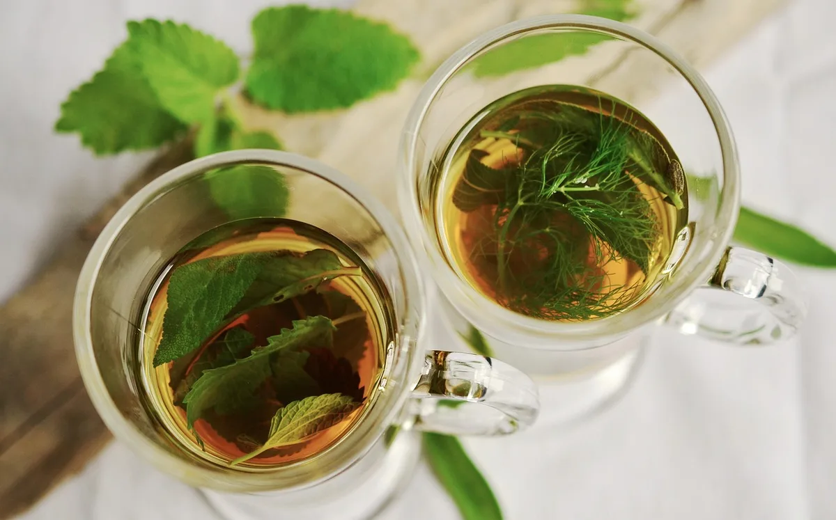 Tasse de thé vert avec feuilles à côté